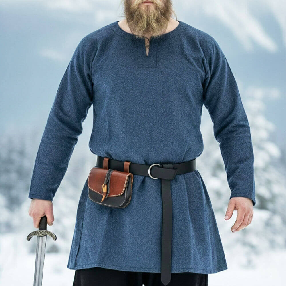 Viking wearing a blue  long-sleeve wool tunic and holding a sword with a snowy background