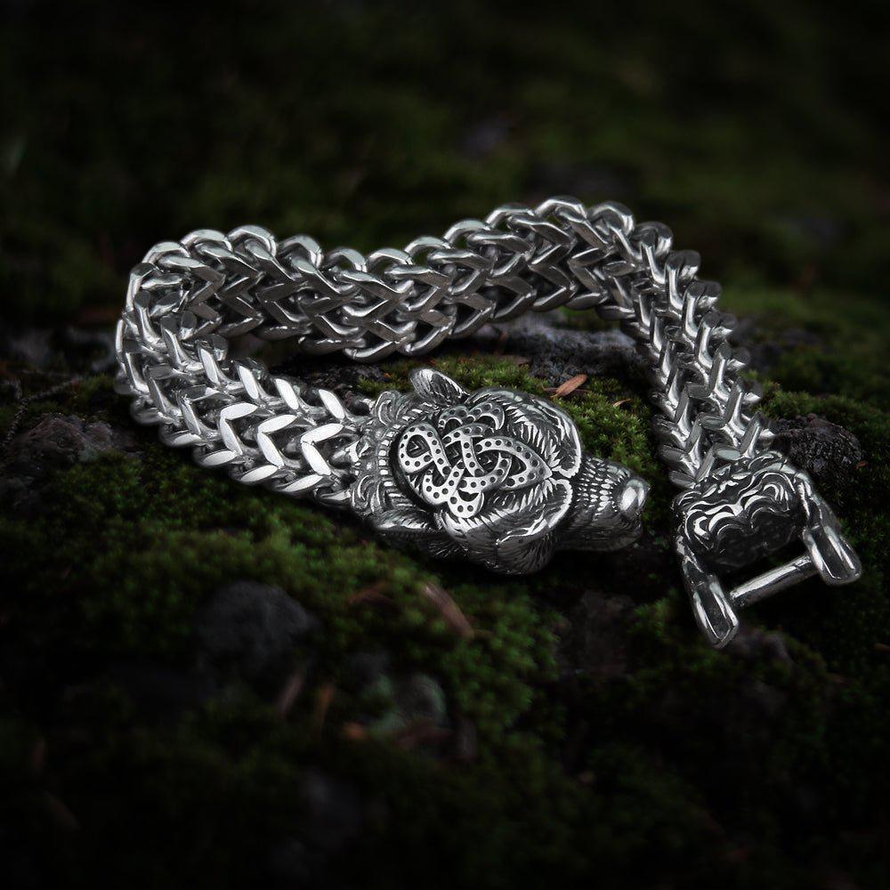 Steel Viking berserker bear head bracelet with intricate knotwork and a thick chain, on moss.