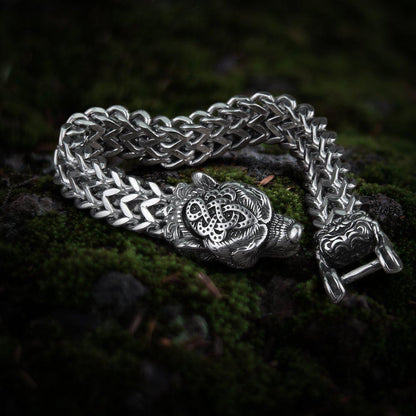 Steel Viking berserker bear head bracelet with intricate knotwork and a thick chain, on moss.