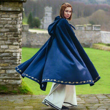 Blue hooded Viking wool blend cloak with gold embroidery, flowing over white pants.