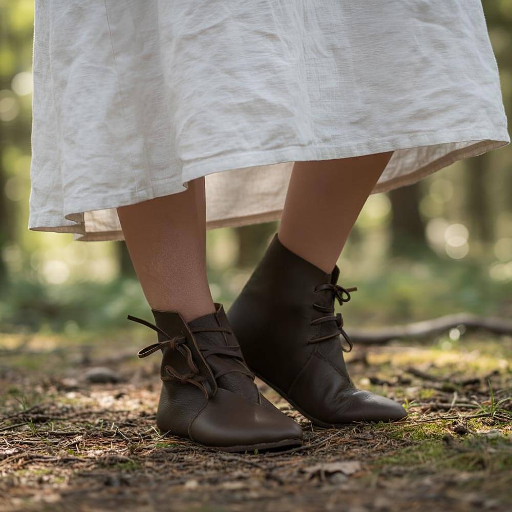 Brown leather boots worn with a white skirt in a forest setting