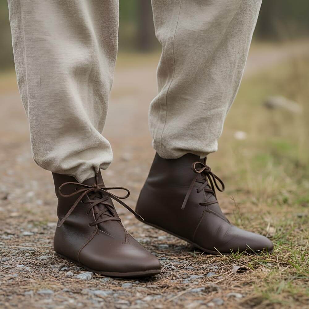 Brown leather Viking ankle boots with four-string lace adjustment, worn outdoors.