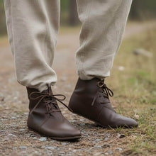 Brown leather Viking ankle boots with four-string lace adjustment, worn outdoors.