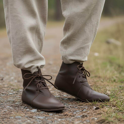 Brown leather Viking ankle boots with four-string lace adjustment, worn outdoors.