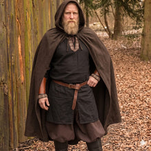 Viking warrior in a brown hooded wool cloak, black tunic with embroidered trim, leather belt, and bracers.