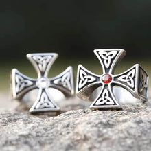 Viking Celtic Trinity Cross rings, silver-tone, one with red stone, one with clear stone, on rock.