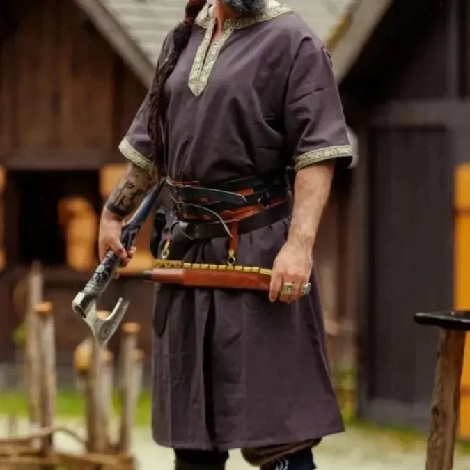 Dark brown Viking tunic with short sleeves and gold embroidered border, worn by a man holding an axe.