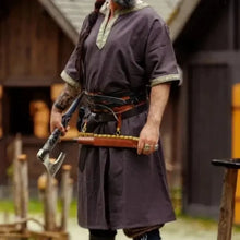 Dark brown Viking tunic with short sleeves and gold embroidered border, worn by a man holding an axe.