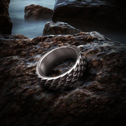 Viking Dragon Scale Modern Steel Ring, silver, textured, on dark rocks.