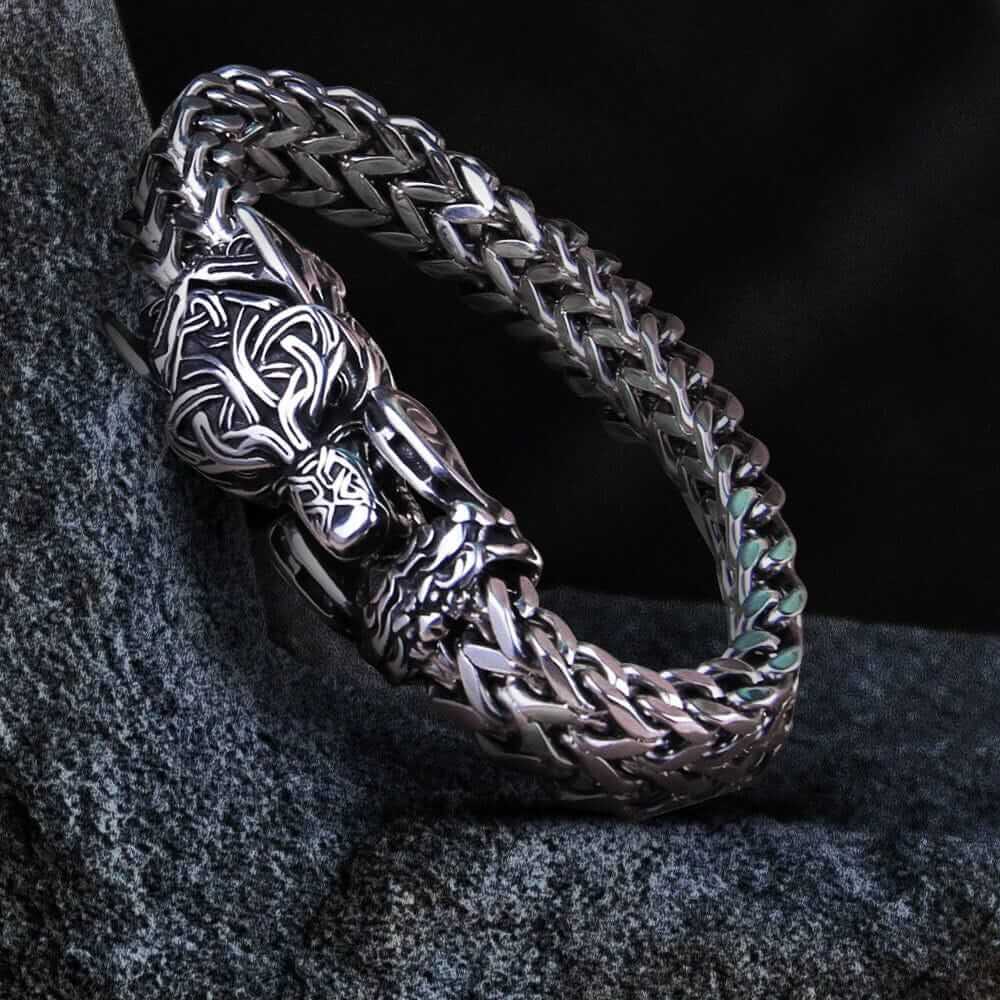 Viking Fenrir wolf head bracelet in polished silver steel with intricate Celtic knotwork and a braided chain.