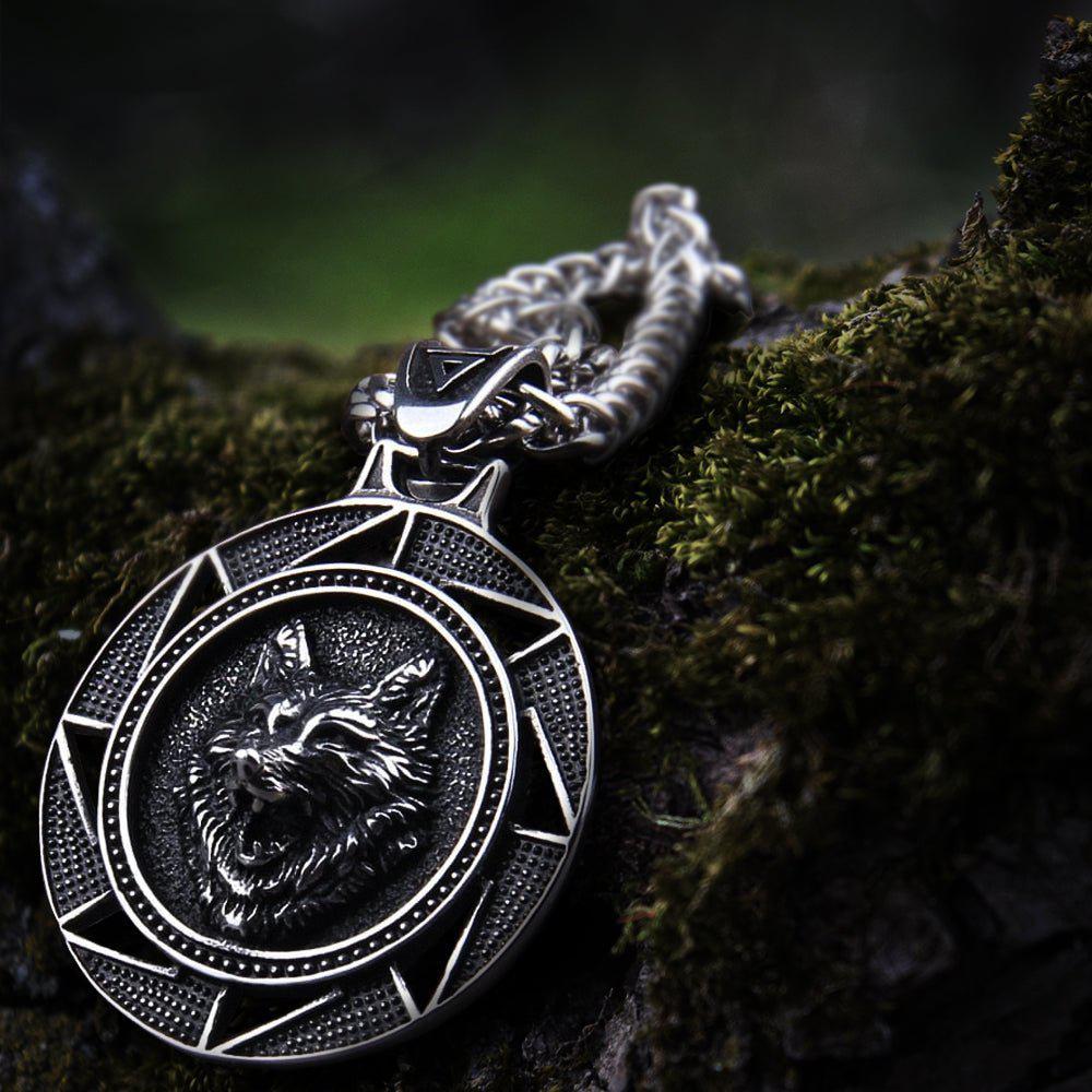 Steel Viking Fenrir wolf medallion necklace on mossy wood.