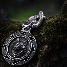 Steel Viking Fenrir wolf medallion necklace on mossy wood.