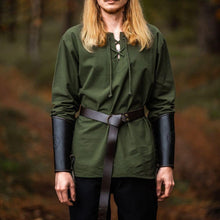 Man wearing a green cotton Viking tunic with long sleeves, lace-up collar, leather belt, and black arm guards in forest setting.