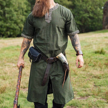 Green Viking tunic with short sleeves, embroidered border, worn with a belt, pouch, and drinking horn.