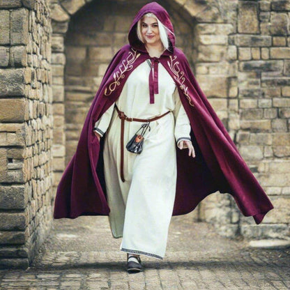 Woman in a flowing red Viking cloak with an embroidered hood, over a white tunic.