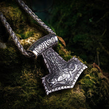 Heavy silver Viking Thor's Hammer necklace with intricate knotwork design on moss.