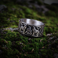 Silver Viking ring with howling wolves, triskele knot, and intricate band design.