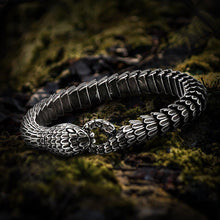 Viking Jormungandr segmented steel bracelet, dark silver, snake head clasp, on mossy ground.