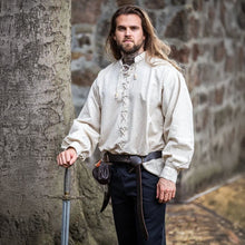 Man in a natural linen Viking shirt with laced front, holding a sword.