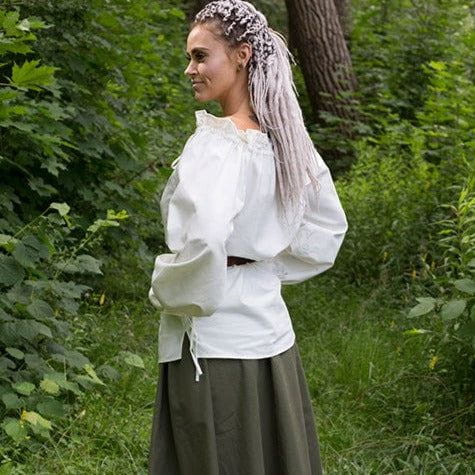 Woman in a white Viking cotton blouse with ruffled neckline and long sleeves, over a dark skirt.