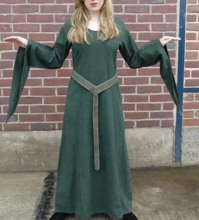 Woman in a long, dark green Viking cotton dress with a light green woven belt.