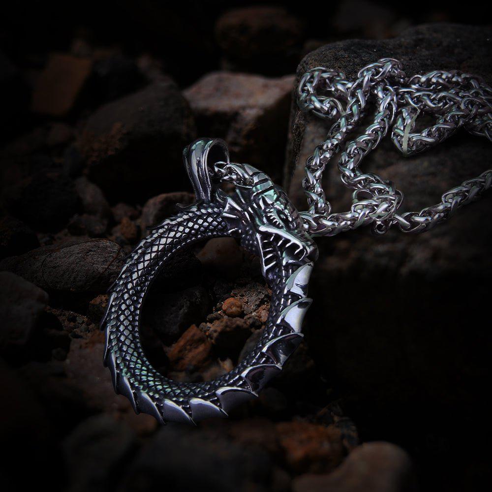 Silver Viking Jormungandr Ouroboros dragon pendant necklace on a dark rocky surface.