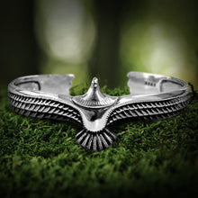 Viking silver eagle torc-style bracelet with detailed wings on green moss.