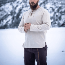 Natural cotton Viking tunic with long sleeves and lace-up collar, worn by a man in snow.