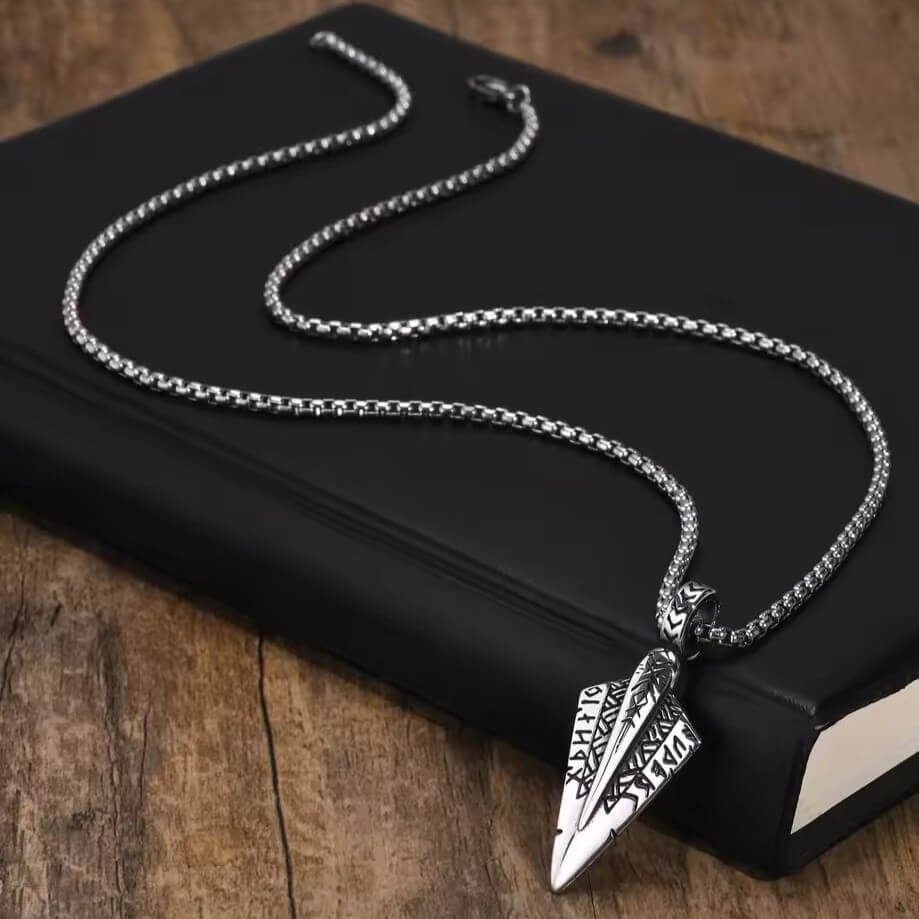 Viking Nordic Tyr spearhead pendant necklace, silver-toned metal with engraved runes, on a chain.