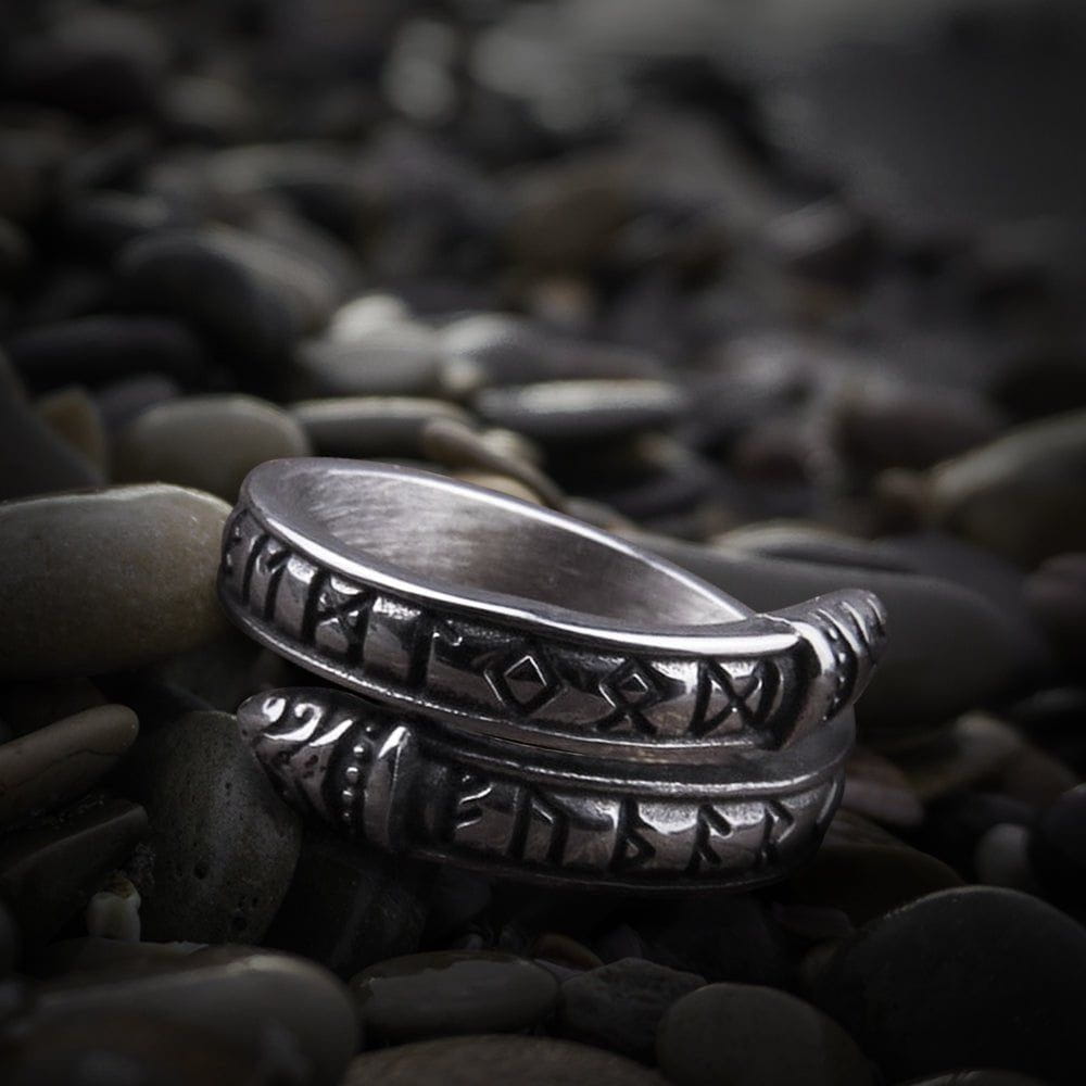 Silver Viking ring with Futhark runes and Midgard Serpent design on dark pebbles.