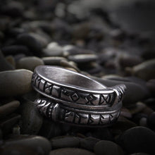 Silver Viking ring with Futhark runes and Midgard Serpent design on dark pebbles.