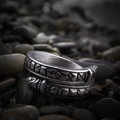Silver Viking ring with Futhark runes and Midgard Serpent design on dark pebbles.