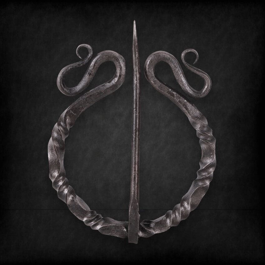 Dark twisted steel Viking penannular cloak clasp with decorative scrolls and a sharp pin.