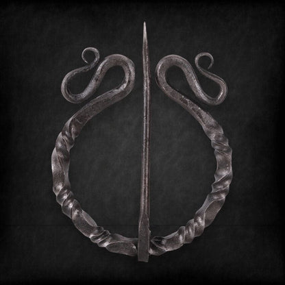Dark twisted steel Viking penannular cloak clasp with decorative scrolls and a sharp pin.