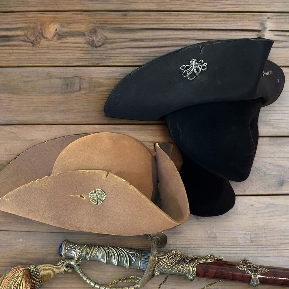 Weathered brown and black Viking pirate tricorn hats with a decorative sword on wood.
