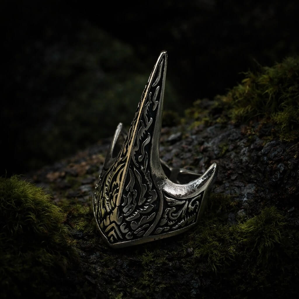 Dark silver Viking Raven Talon ring with intricate carvings on mossy wood.