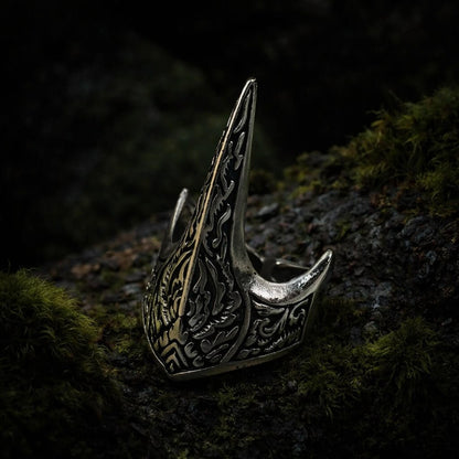 Dark silver Viking Raven Talon ring with intricate carvings on mossy wood.