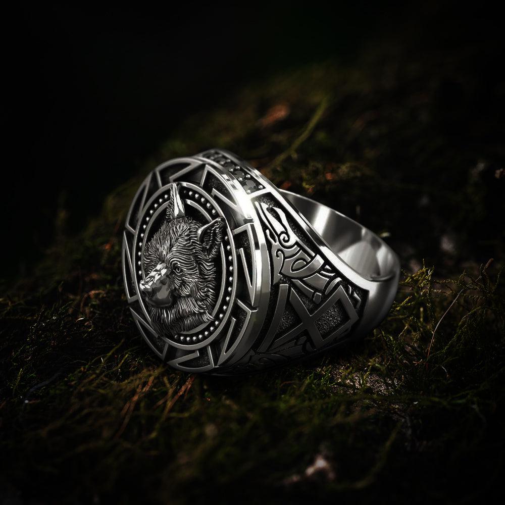 Silver Viking wolf head totem ring with intricate geometric patterns on moss.