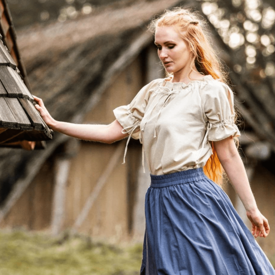 Viking woman in a natural linen short sleeve blouse with lace-up neckline and a blue skirt.