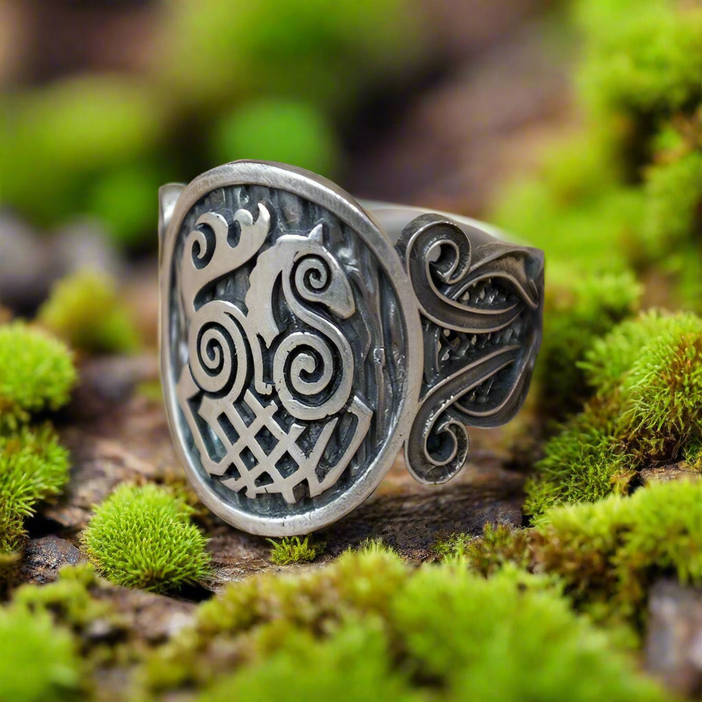 Sterling silver Viking ring with Sleipnir symbol and Norse ornament on mossy wood.