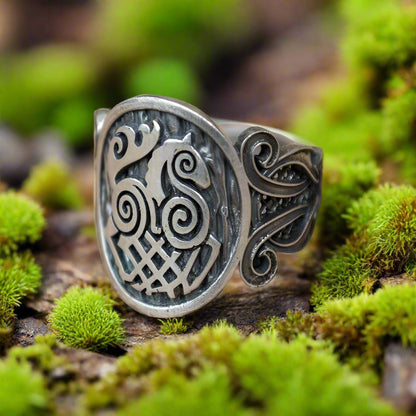 Sterling silver Viking ring with Sleipnir symbol and Norse ornament on mossy wood.