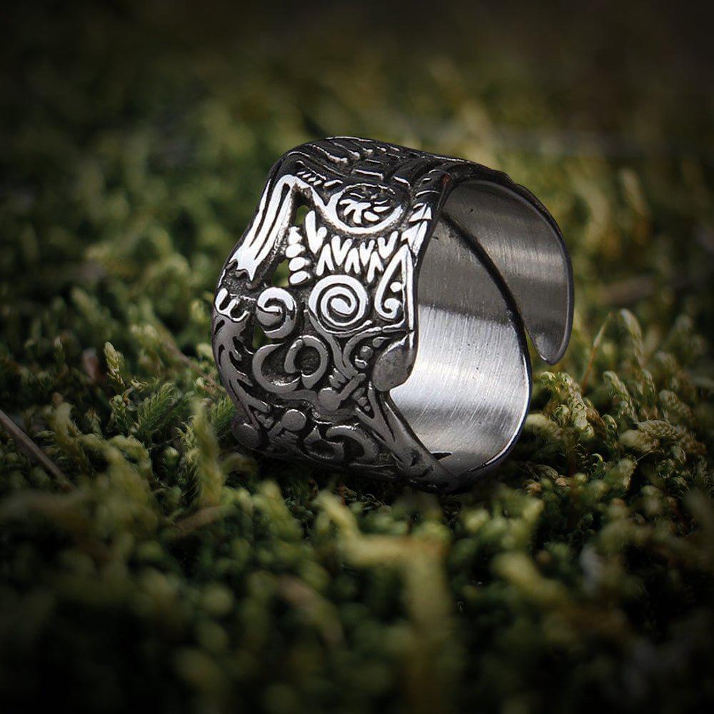 Stainless steel Viking Odin wolf ring with intricate Nordic knotwork on moss.