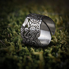 Stainless steel Viking Odin wolf ring with intricate Nordic knotwork on moss.