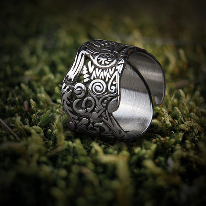 Stainless steel Viking Odin wolf ring with intricate Nordic knotwork on moss.