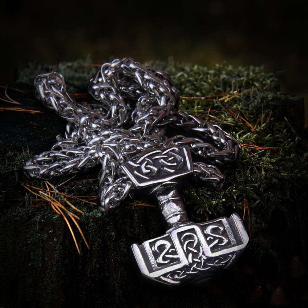 Viking steel Mjolnir pendant necklace with intricate knotwork design on a dark mossy background.