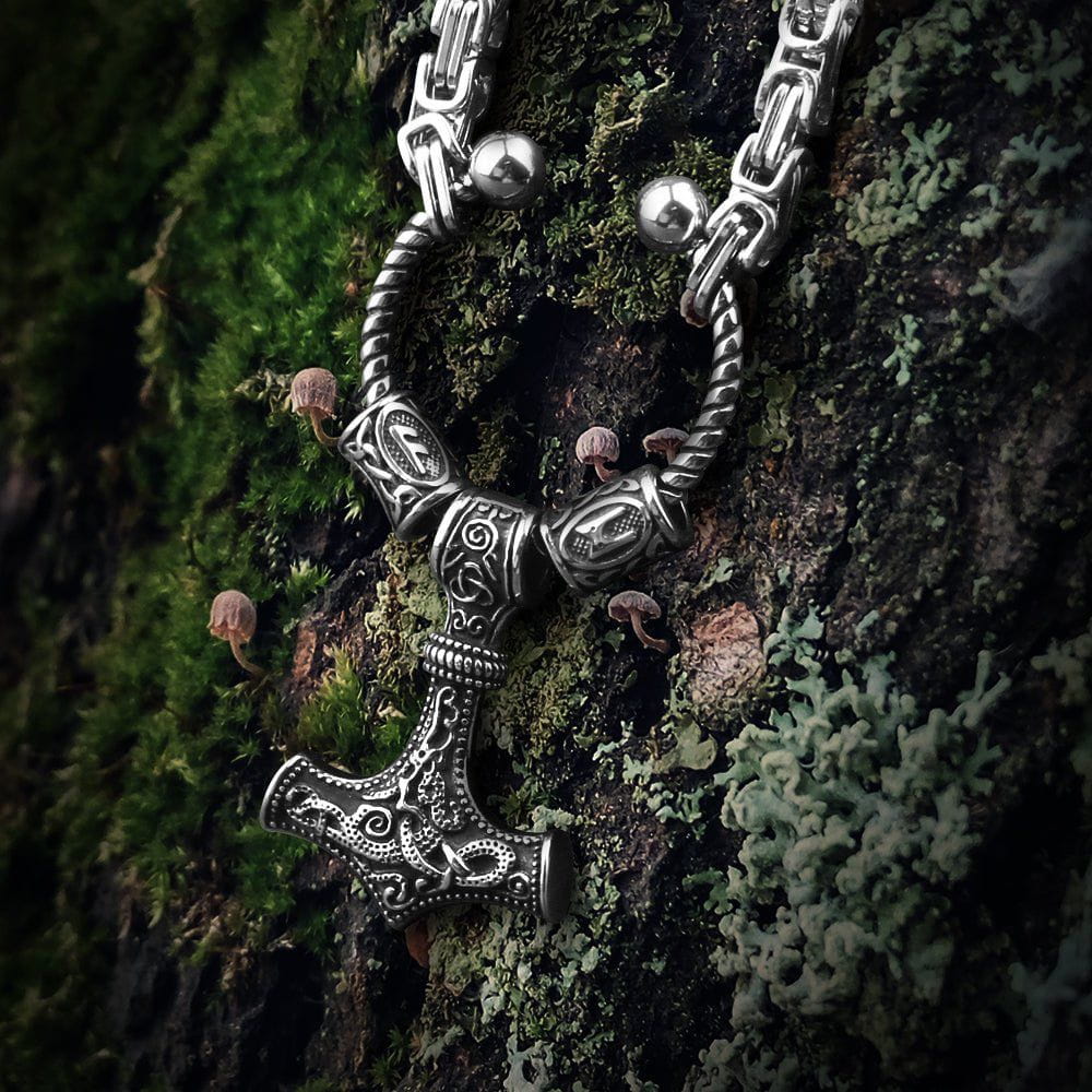 Viking steel Mjolnir Futhark rune bead King's Chain on mossy bark.