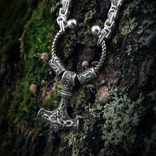 Viking steel Mjolnir Futhark rune bead King's Chain on mossy bark.