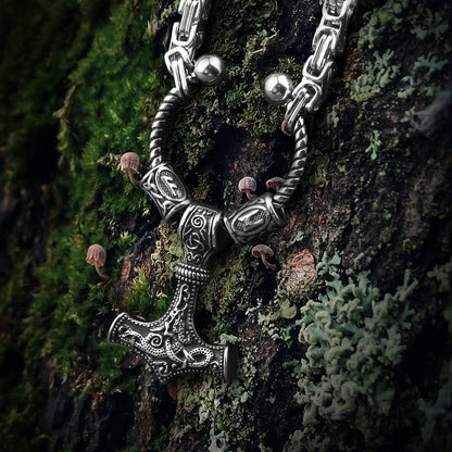 Viking steel Mjolnir Futhark rune bead King's Chain on mossy bark.