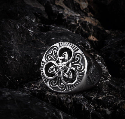 Silver Viking knotwork triskelion ring on dark rock.