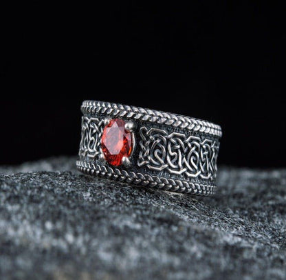Sterling silver Viking ring with intricate Celtic knotwork and a vibrant red gemstone.
